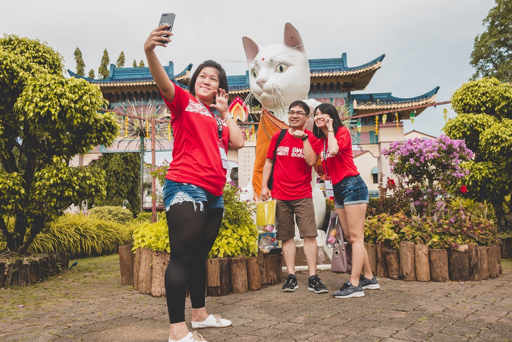 Partners posing in front of the cat statue as part of the Amazing Meow Hunt challenge.