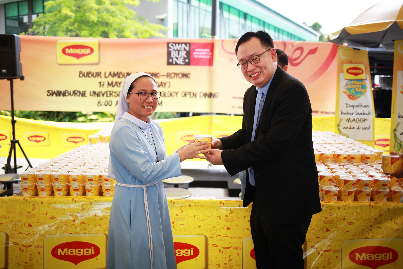 Ir. Professor Lau (right) distributing the container of bubur lambuk to a representative from Sarawak Cheshire Home.