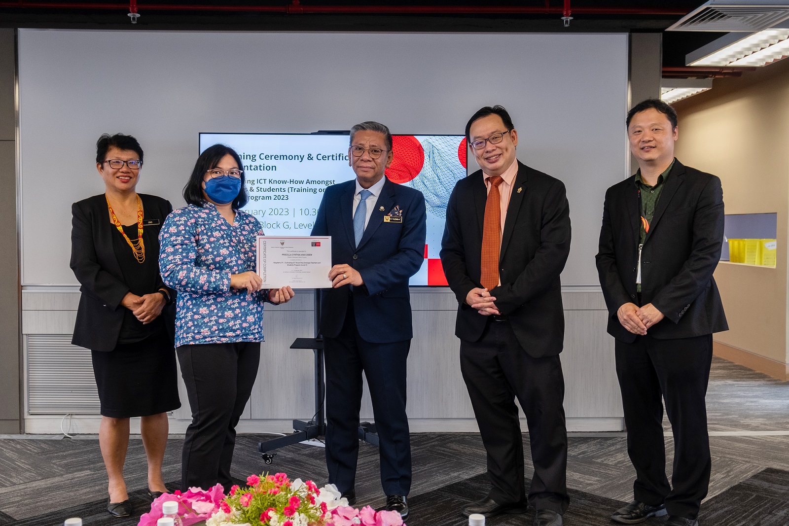 Tuan Haji Azmi (centre) presents a certificate of completion to a teacher as (from left) Dr Ong, Professor Lau and Professor Wong look on. 