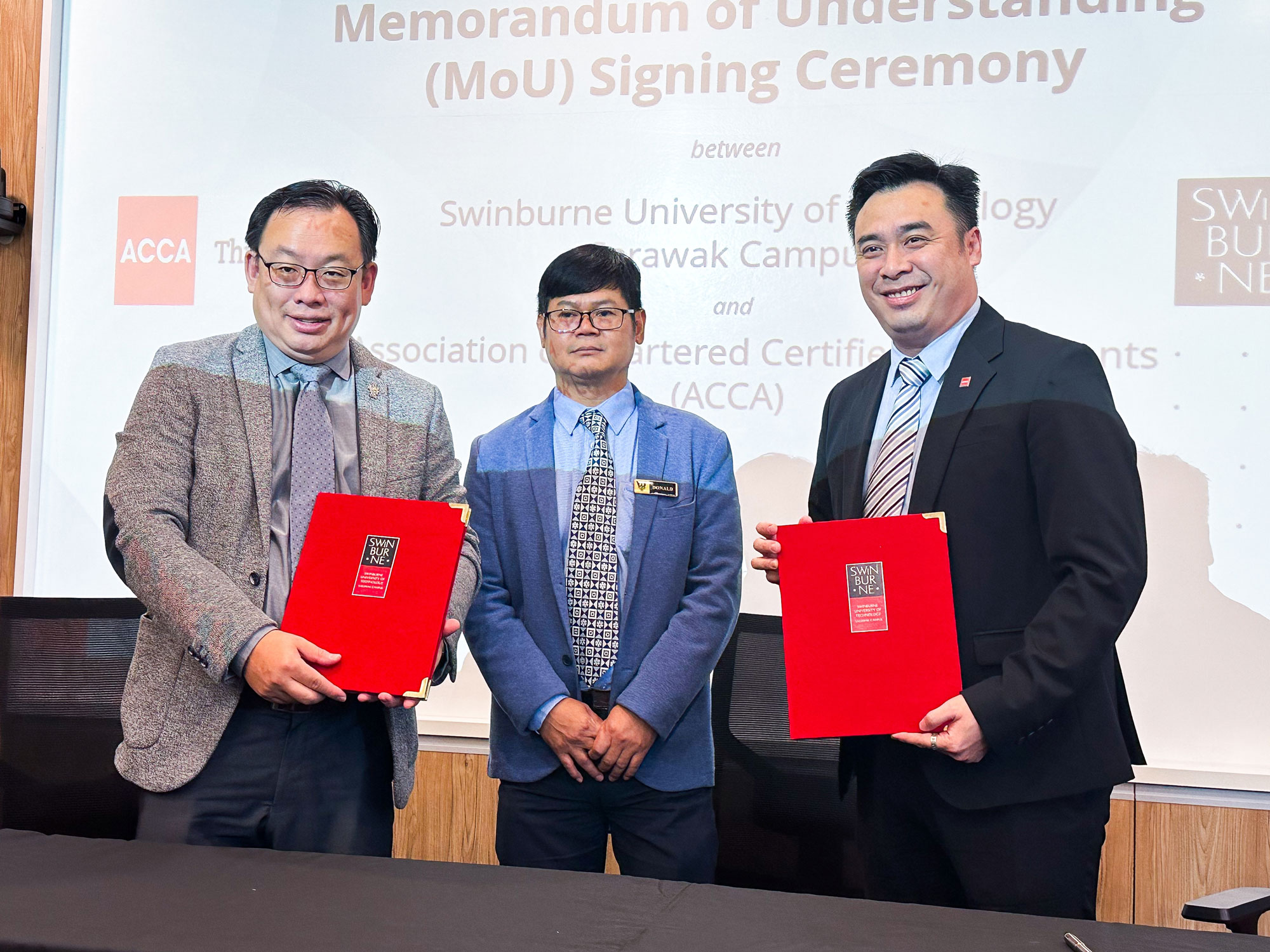Ir Professor Lau Hieng Ho (left) and Mr Andrew Lim (right) show the signed documents as Mr Donald Henry Nohed looks on.