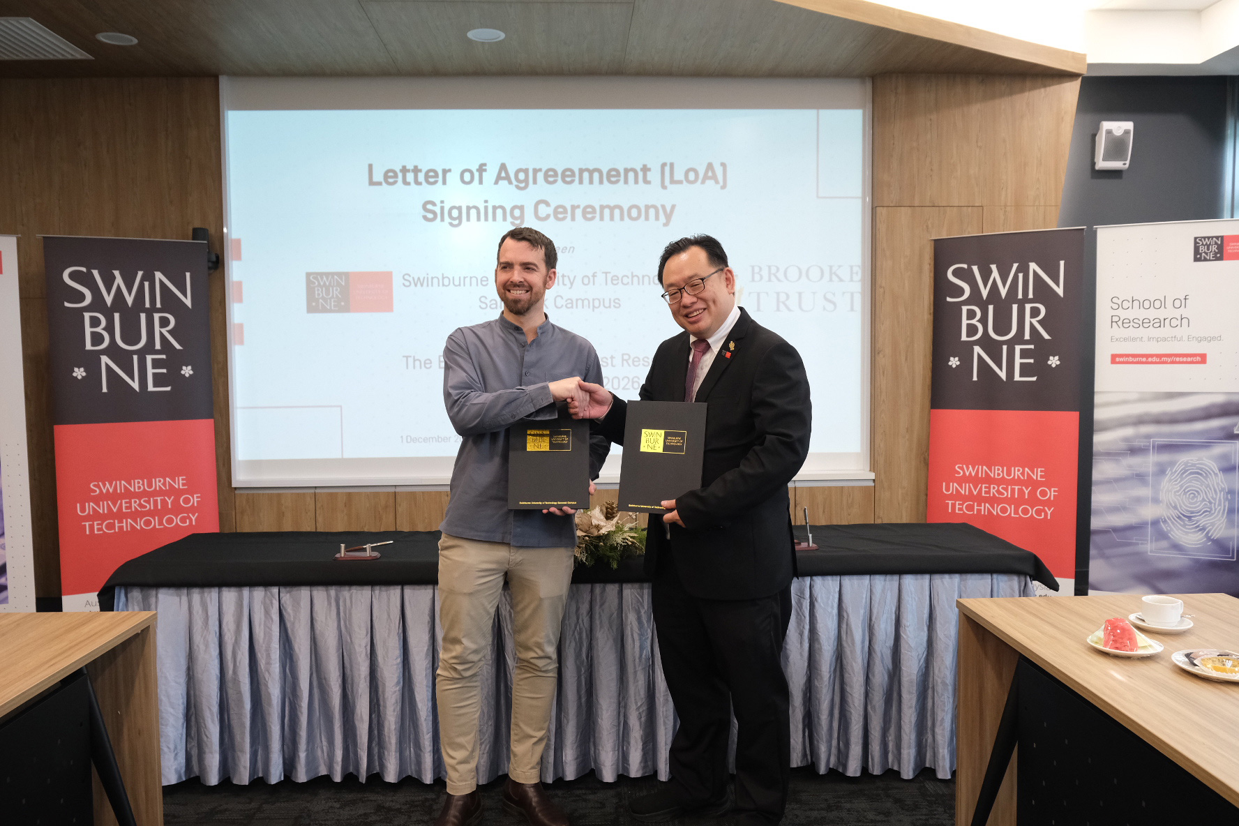 Mr Jason Brooke (left) and Ir Professor Lau Hieng Ho hold up the signed LoA.