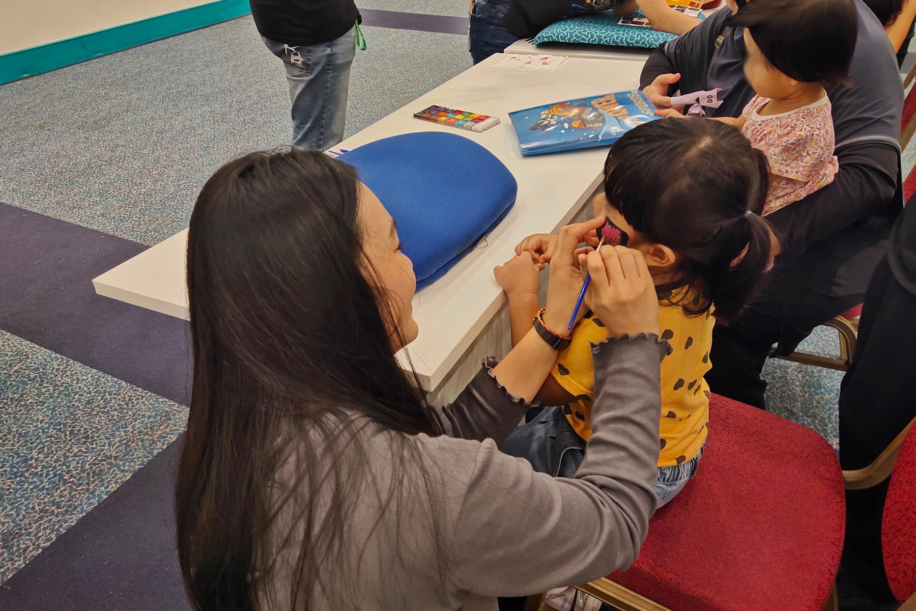 Racqle paints one of the children’s faces.