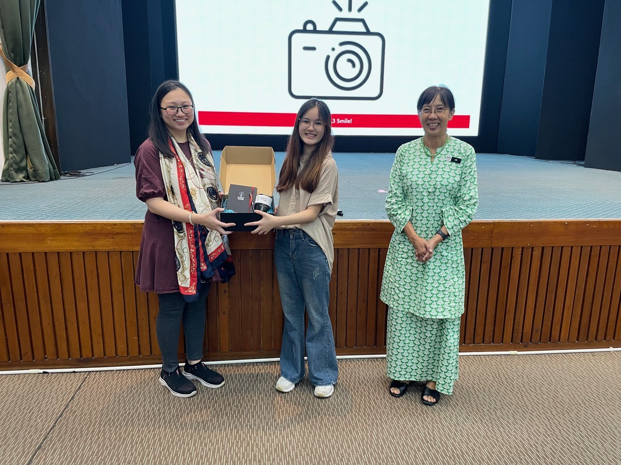 (02) An exchange of tokens of appreciation between Rakan Tutor Outreach Associate Jocelyn Wong, and Dr Miko Chang witnessed by Cikgu Belinda Lim of SMK St Joseph