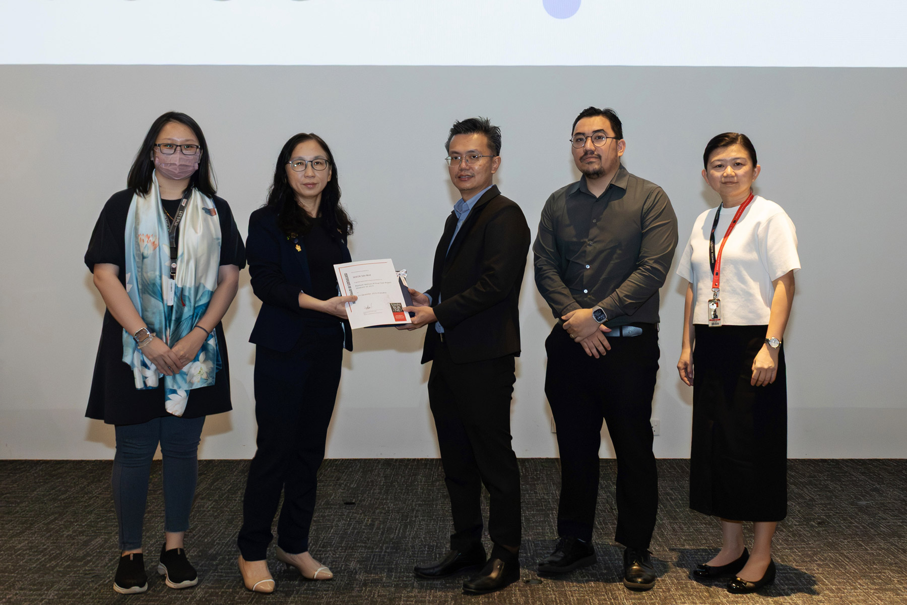 Ts Professor Lau Bee Theng (second left), Associate Dean of Research and Development, presents a token of appreciation to Mr Lai Chee Ping (centre) and Mr Abdul Najib Azhfar Aini (second right) of SOCOE Sdn Bhd, representing the Platinum Sponsor.