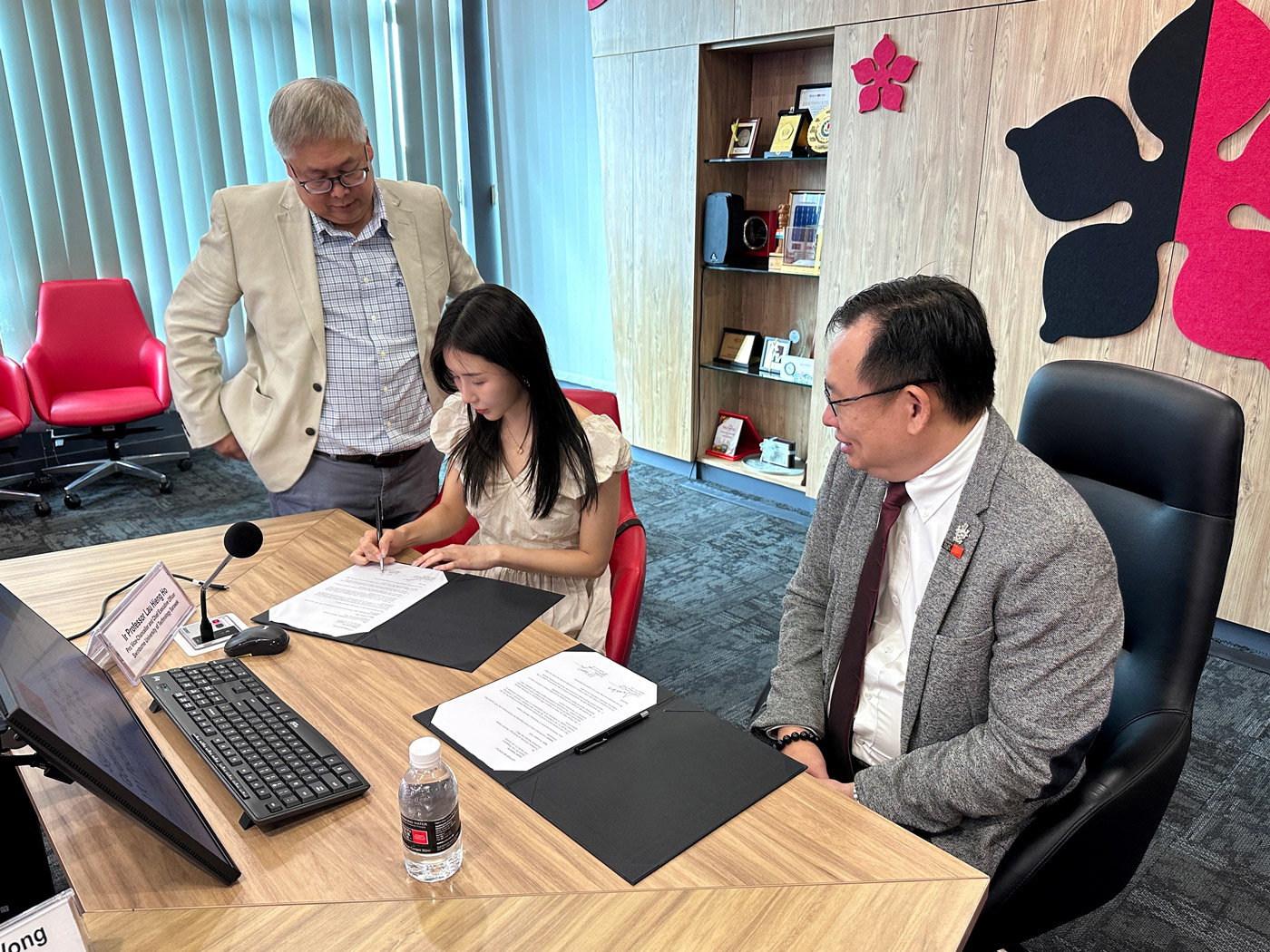 Yery Chung (centre), signing the Letter of Intent at Swinburne Sarawak, overlooked by Gerald Leong (left) and witnessed by Ir Professor Lau Hieng Ho (right). 