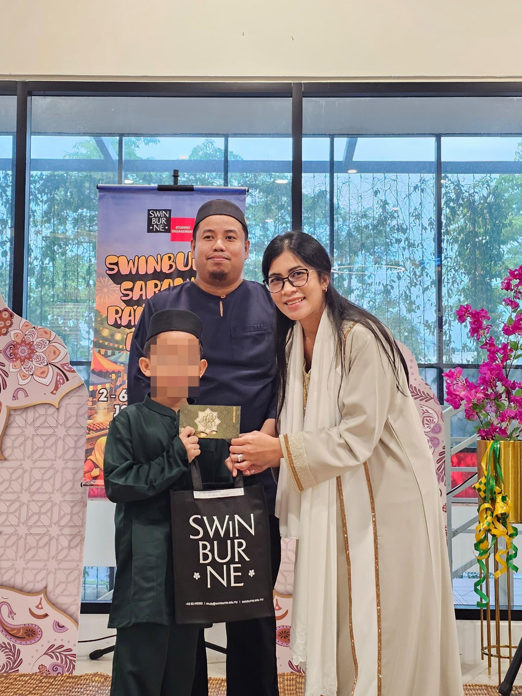 Professor Dr Ida Fatimawati Bt Adi Badiozaman (right) presents gifts to one of the children from Pertubuhan Kebajikan Baiturrahmah, as Pertubuhan Kebajikan Baiturrahmah House Warden Encik Muhammad Al-Hasyer Bin Abdullah Sani looks on. 