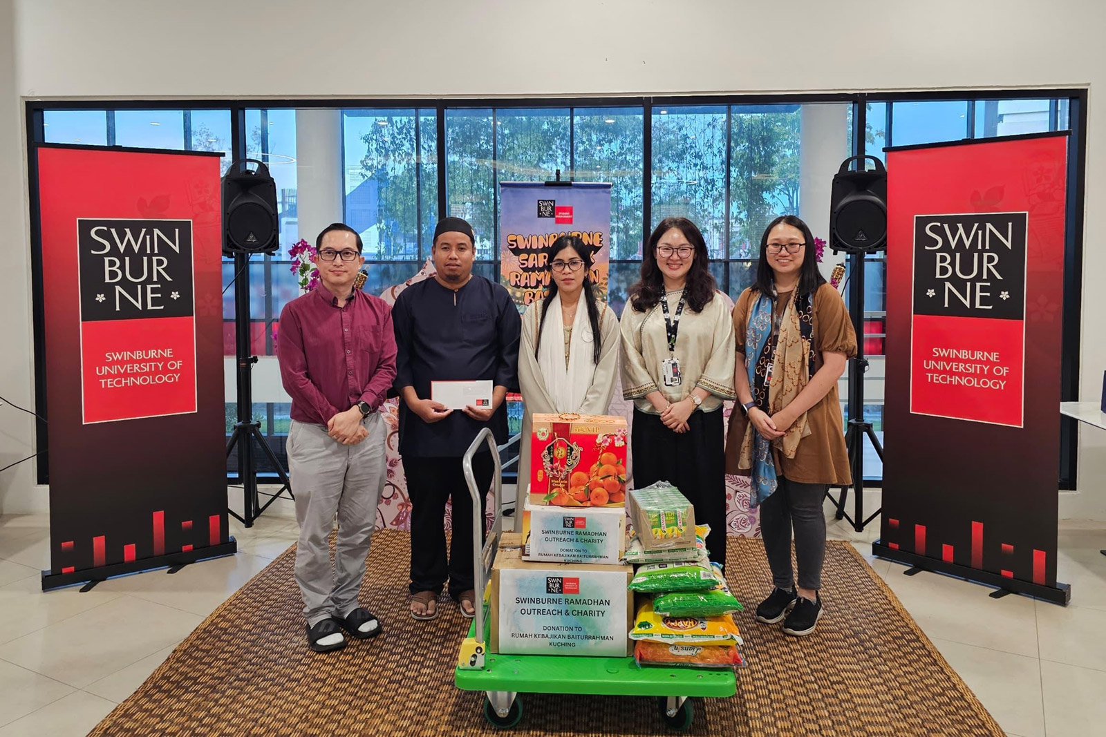 The donations are presented to Pertubuhan Kebajikan Baiturrahmah. Seen are Professor Dr Ida Fatimawati Bt Adi Badiozaman (centre), Pertubuhan Kebajikan Baiturrahmah House Warden Encik Muhammad Al-Hasyer Bin Abdullah Sani (second from left), and other representatives from Swinburne Sarawak. 
