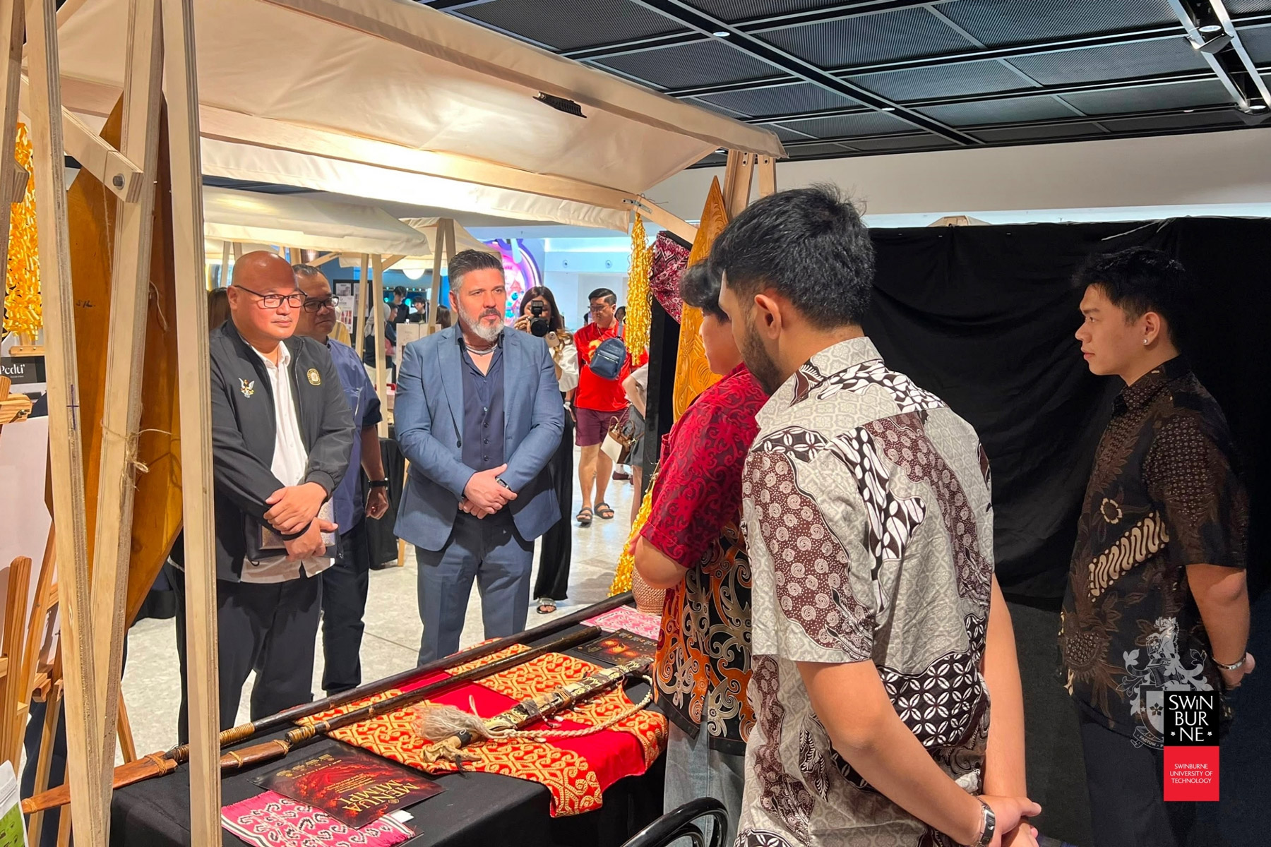 Raca Mulong (left) tours the exhibition with Associate Professor Dr Predrag Nikolic (centre), Head of the School of Design and Arts at Swinburne Sarawak.