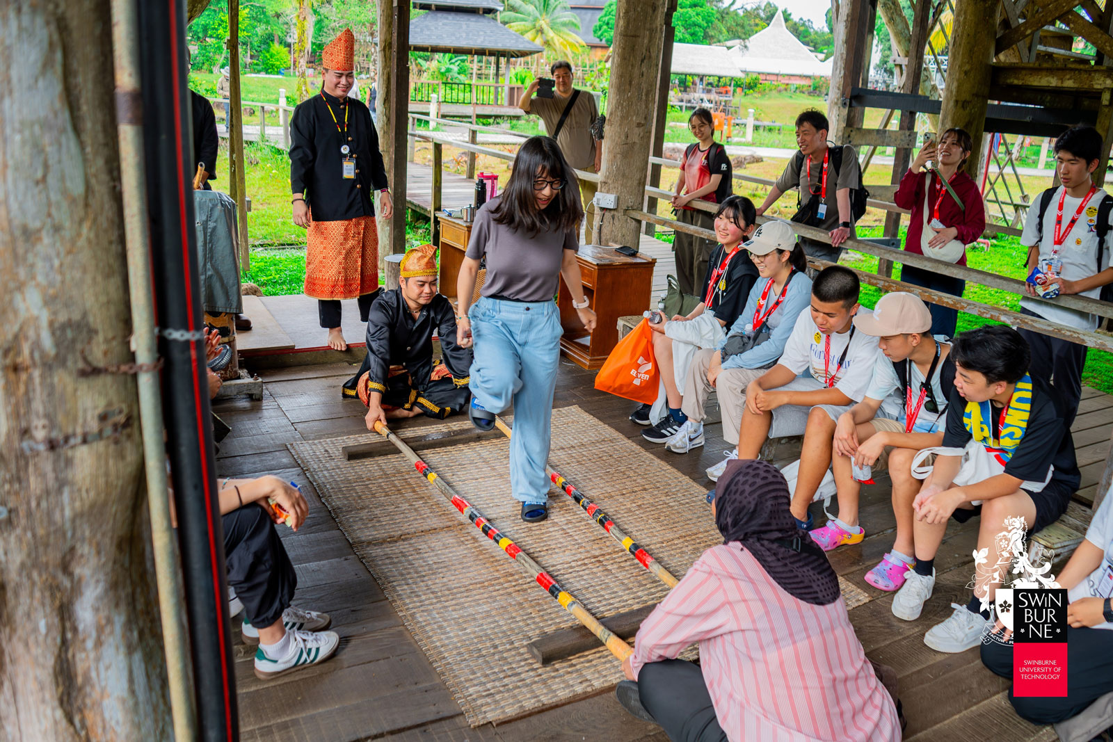 A student tries out a traditional dance at the Sarawak Cultural Village.